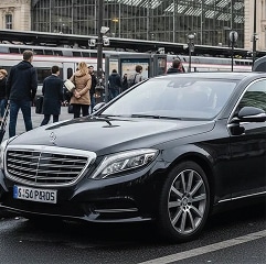 Mercedes Classe S noire à Paris : Luxe devant la gare Mercedes Classe S noire luxueuse devant une gare parisienne avec plaque d'immatriculation S 500 PARIS.