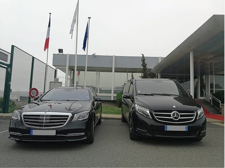 Chauffeur privé VTC Mercedes Classe S et V en France Berline Mercedes Classe S et van Classe V noirs devant un bâtiment officiel avec drapeaux français et européen.